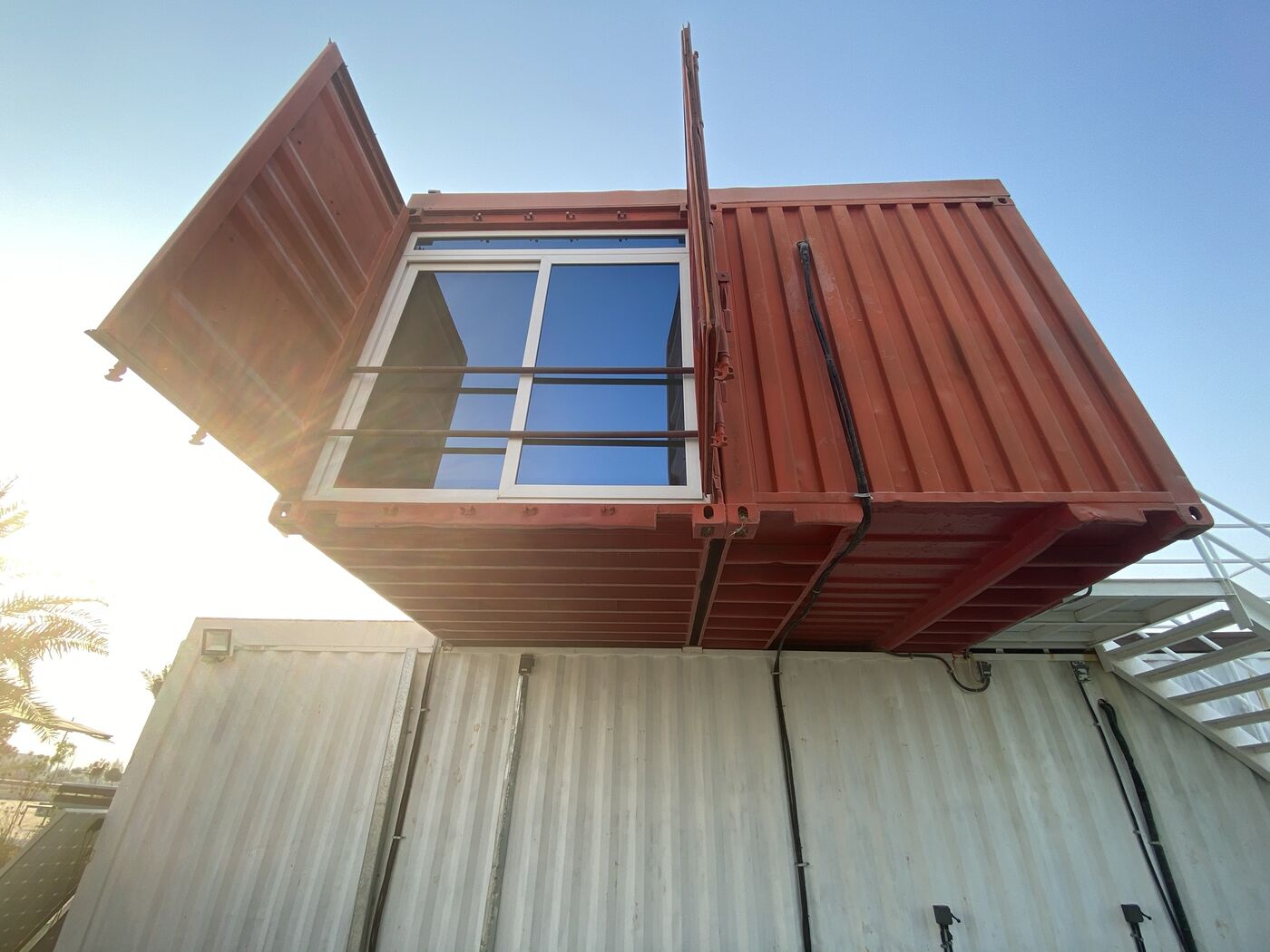 Converted shipping container with a large sliding window, stacked on another container
