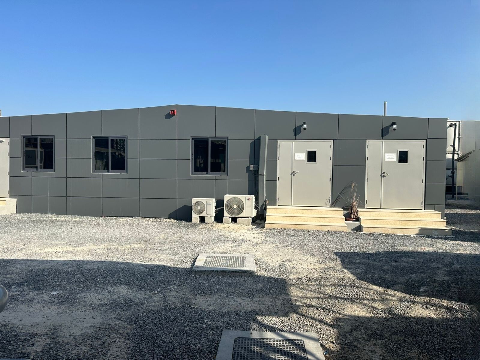 Single-storey modular office building with grey cladding panels, windows and double doors